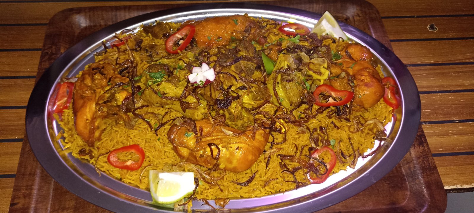 Whole chicken mandi platter with saffron rice, chili and lemon garnish