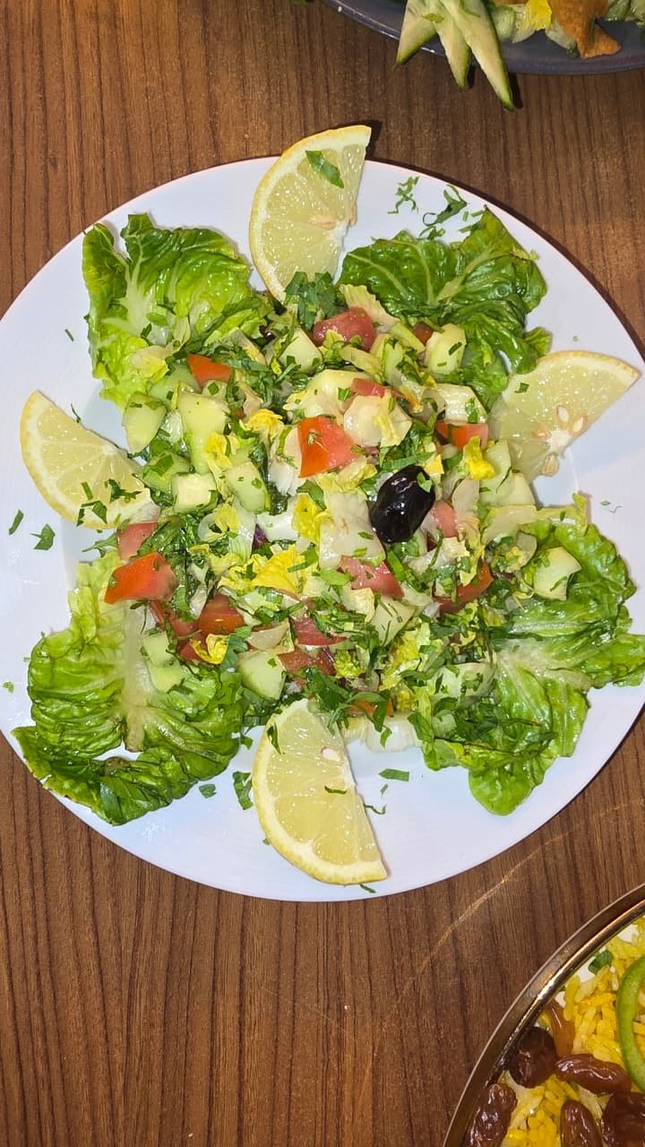 Fresh green salad with lemon wedges and olives