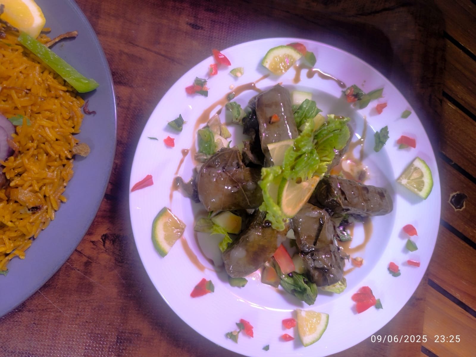Stuffed grape leaves plated with lemon and fresh herbs