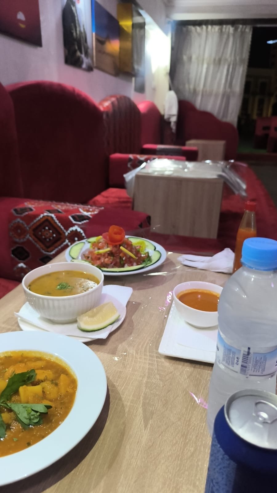 Cozy lounge seating at Khaymat Al Mandi with traditional cushions, soup and salad on the table