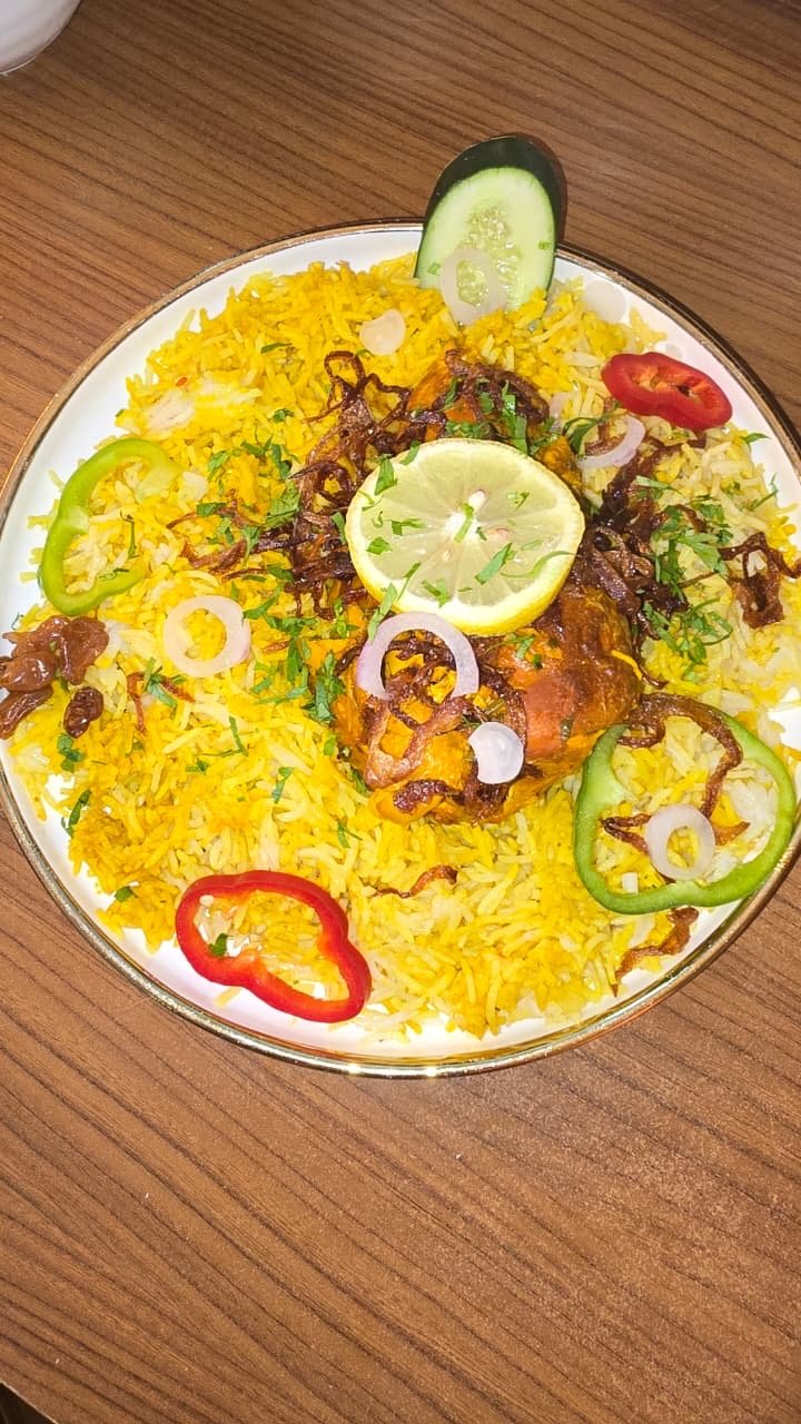 Chicken quarter over saffron rice with pepper and onion garnish