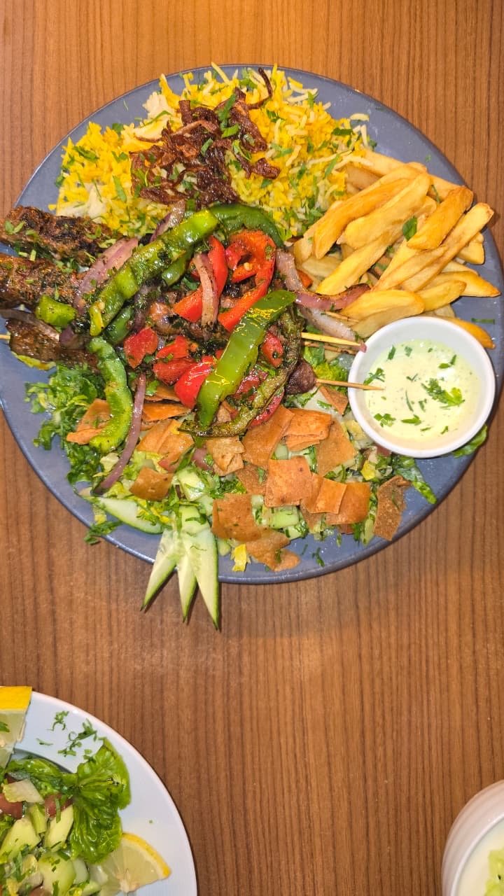 Grilled meat skewers with saffron rice, fries and salad