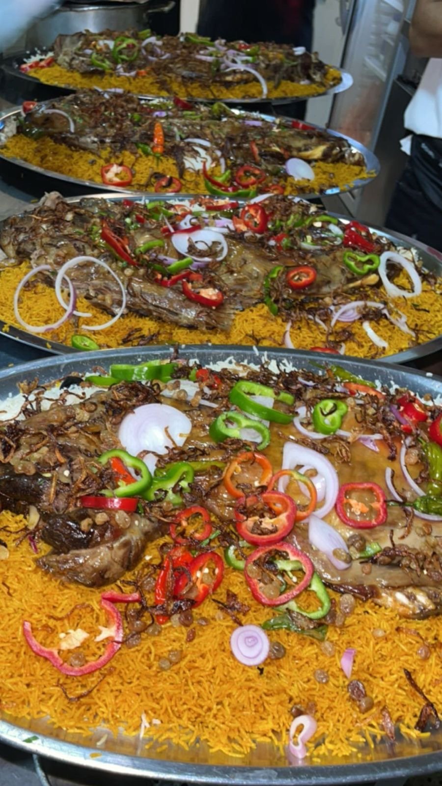Trays of whole roasted meat over saffron rice, prepared in the kitchen